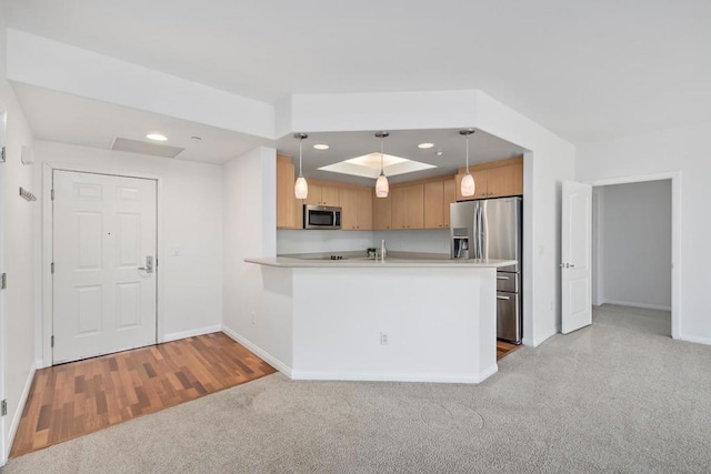 kitchen featuring appliances with stainless steel finishes, light colored carpet, kitchen peninsula, pendant lighting, and light brown cabinetry