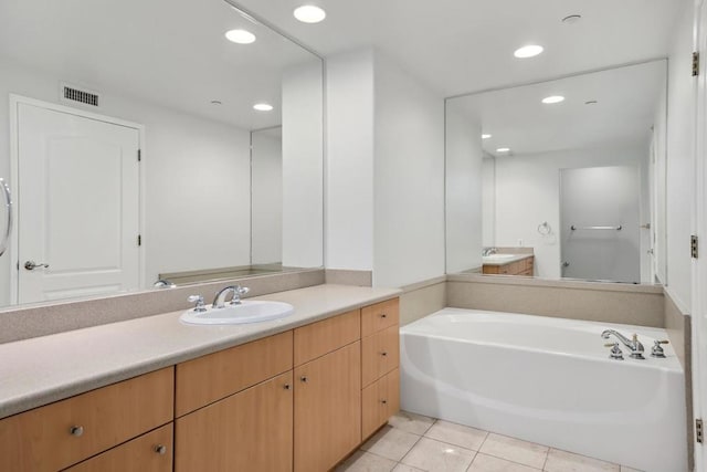 bathroom featuring vanity, a washtub, and tile patterned floors