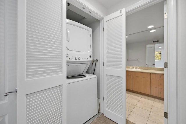 washroom with sink, stacked washer and clothes dryer, and light tile patterned floors