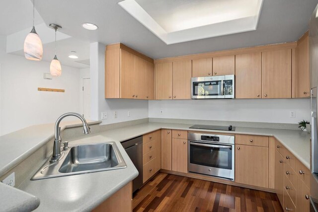 kitchen with sink, light brown cabinetry, hanging light fixtures, and appliances with stainless steel finishes