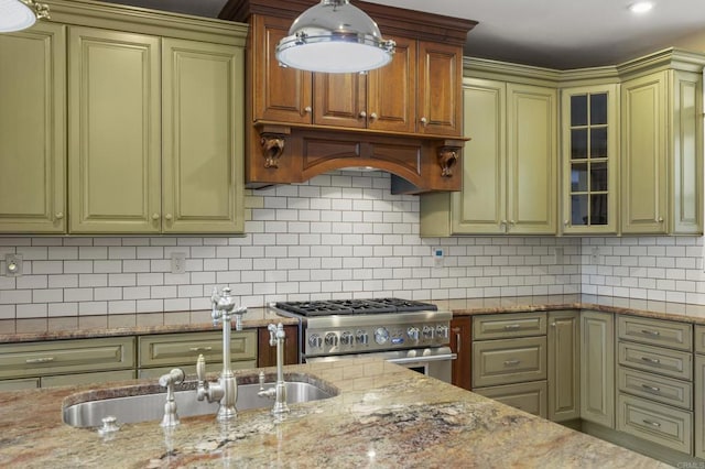 kitchen with hanging light fixtures, stainless steel stove, light stone countertops, sink, and backsplash