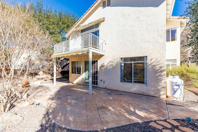 rear view of house featuring a balcony and a patio