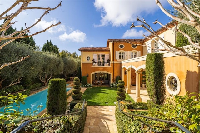 rear view of property featuring a balcony and a yard