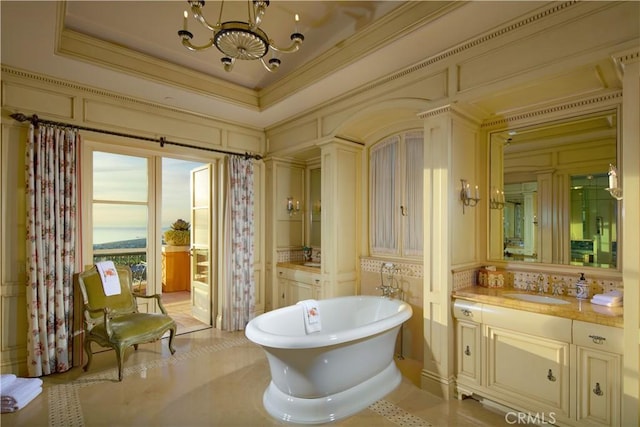 bathroom featuring ornamental molding, a notable chandelier, a bathtub, and vanity