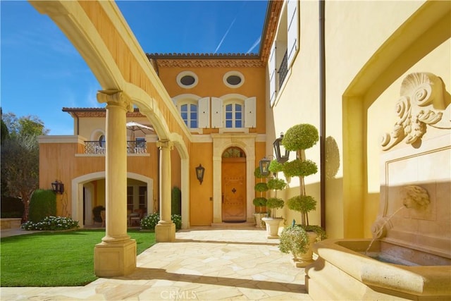 doorway to property featuring a lawn and a patio area