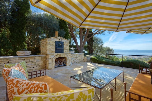 view of patio / terrace featuring a water view and an outdoor living space with a fireplace