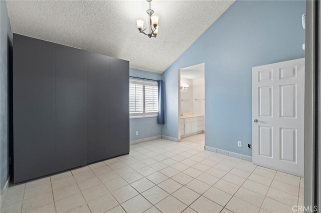 tiled spare room featuring a notable chandelier, lofted ceiling, and a textured ceiling