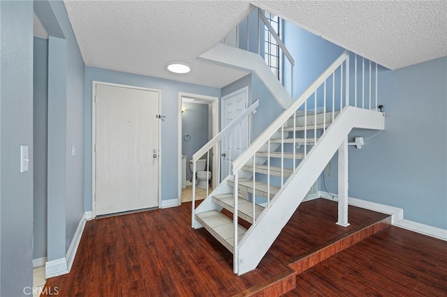 stairs with a textured ceiling and hardwood / wood-style flooring