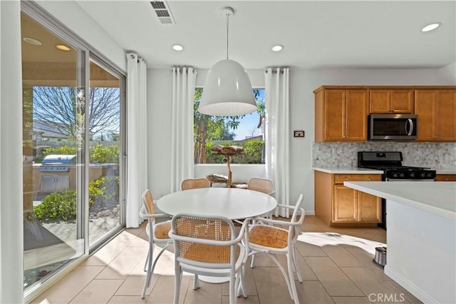 kitchen featuring light tile patterned flooring, tasteful backsplash, pendant lighting, and appliances with stainless steel finishes