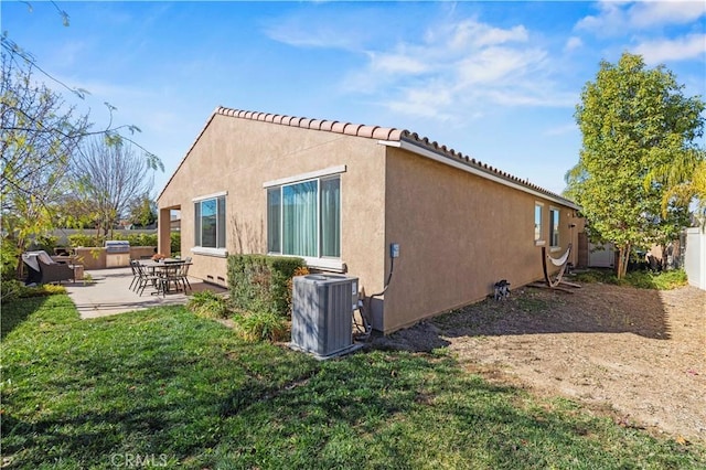 rear view of property with a patio, central AC unit, and a yard