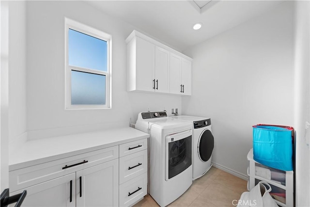 laundry room featuring light tile patterned floors, cabinets, and washer and clothes dryer