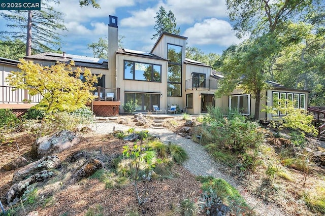 back of property featuring solar panels and a deck