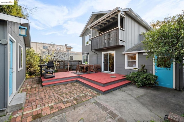 rear view of property with a wooden deck, a balcony, and a patio