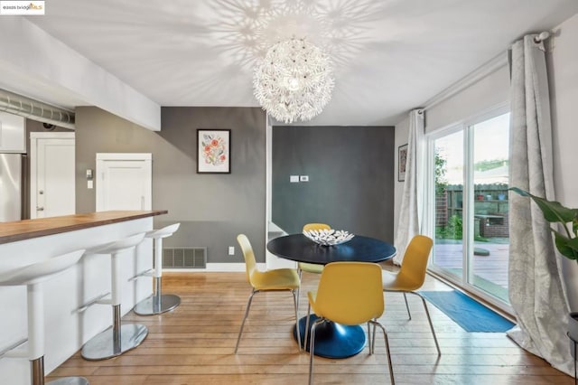 dining space with light hardwood / wood-style flooring and an inviting chandelier