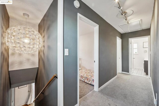 hallway featuring light colored carpet and a notable chandelier