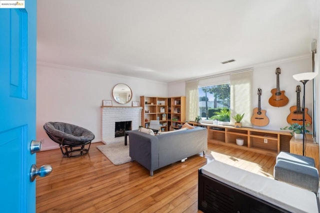 living room with ornamental molding, a fireplace, and light hardwood / wood-style flooring