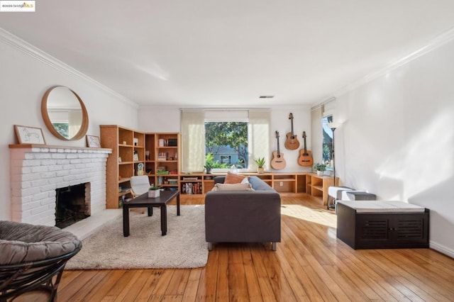 living room with light wood-type flooring, a brick fireplace, and crown molding