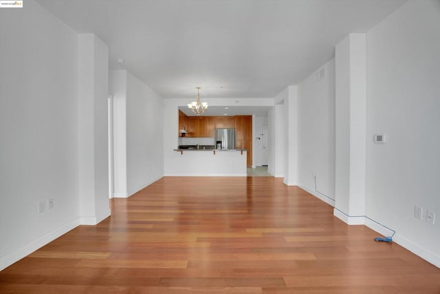 unfurnished living room featuring a chandelier and light hardwood / wood-style floors