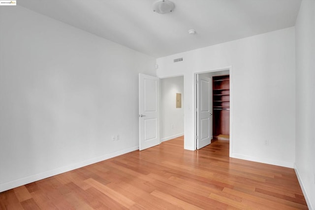 unfurnished bedroom featuring a walk in closet, a closet, and light hardwood / wood-style floors