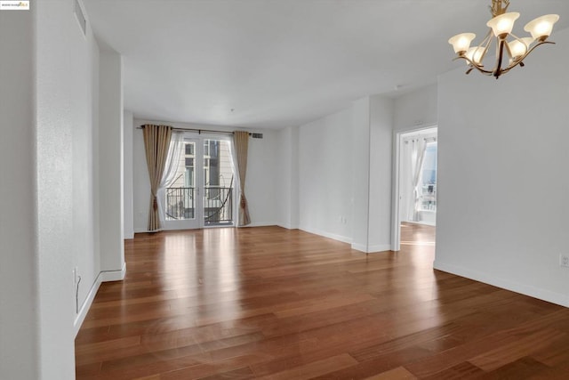 unfurnished room featuring dark hardwood / wood-style flooring and a notable chandelier