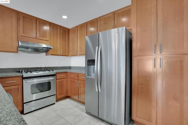 kitchen with appliances with stainless steel finishes, light stone countertops, and light tile patterned floors