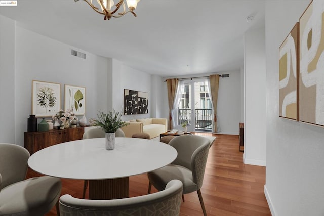 dining area with light hardwood / wood-style floors and an inviting chandelier