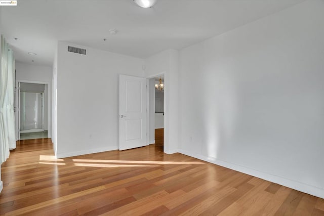 empty room featuring an inviting chandelier and wood-type flooring