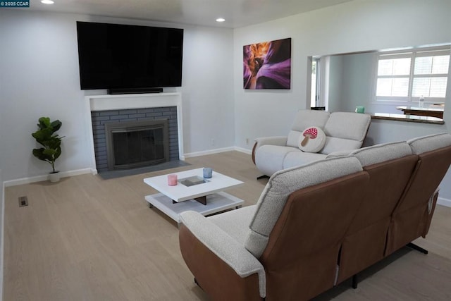 living room featuring a brick fireplace and light hardwood / wood-style flooring