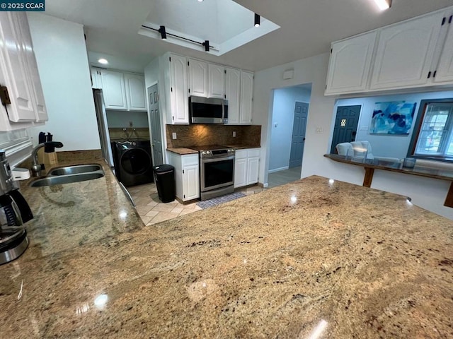 kitchen featuring stainless steel appliances, white cabinetry, and washer / dryer