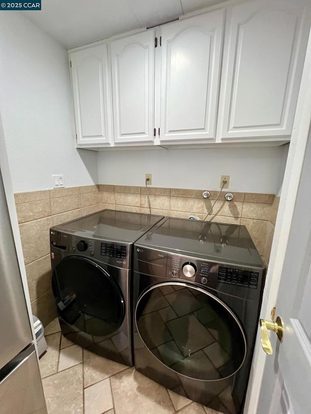 clothes washing area with light tile patterned floors, cabinets, and independent washer and dryer