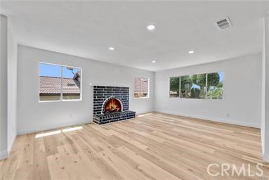 unfurnished living room with a brick fireplace and hardwood / wood-style flooring