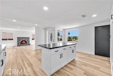 kitchen with a fireplace, a center island, light hardwood / wood-style floors, and white cabinetry