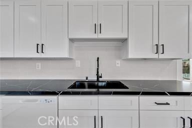 kitchen featuring sink, white dishwasher, white cabinets, and decorative backsplash