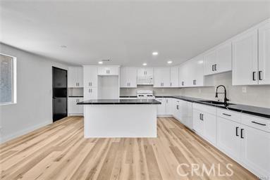 kitchen with white cabinets, a center island, and light hardwood / wood-style flooring