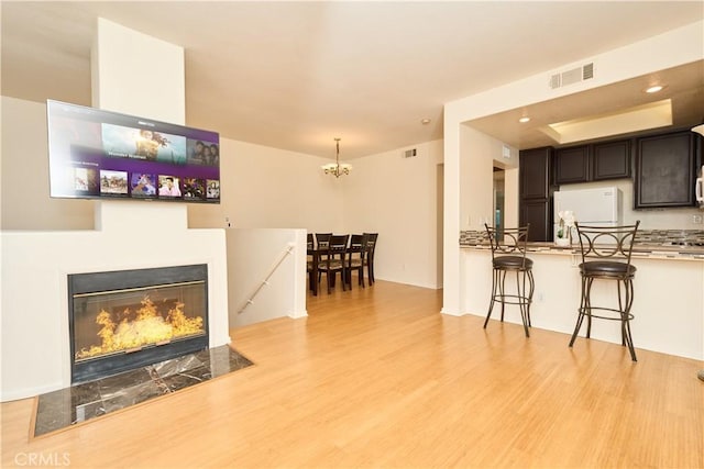 interior space with a fireplace, light wood-type flooring, and an inviting chandelier