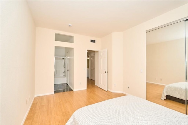 bedroom with wood-type flooring, connected bathroom, and a closet