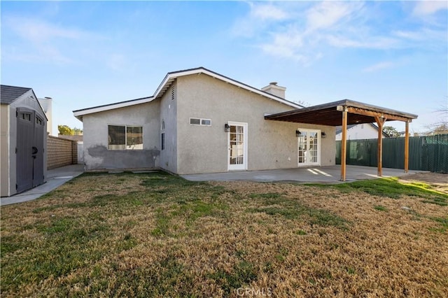 back of house featuring a lawn, a patio, a storage unit, and french doors