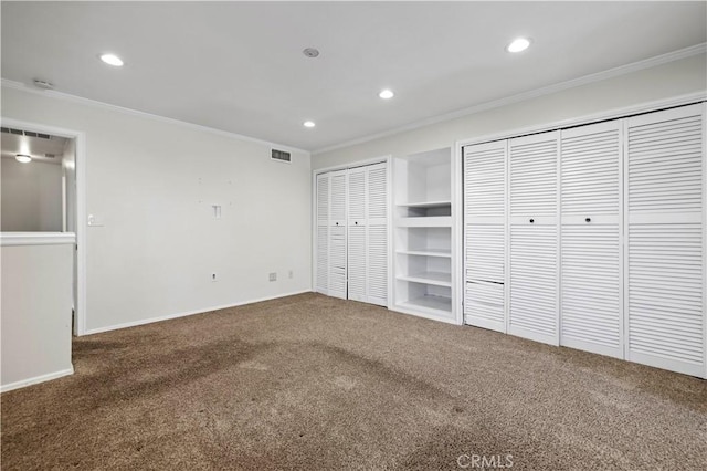 unfurnished bedroom featuring multiple closets, ornamental molding, and carpet floors