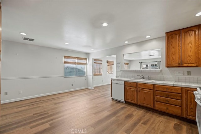 kitchen with sink, white appliances, tile countertops, and light wood-type flooring