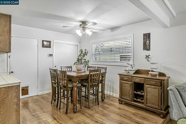 dining room featuring beam ceiling, ceiling fan, and light hardwood / wood-style flooring