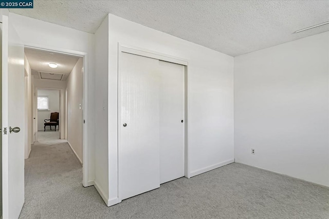 unfurnished bedroom featuring a closet, a textured ceiling, and light colored carpet