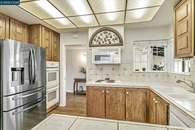 kitchen featuring sink, white appliances, and backsplash