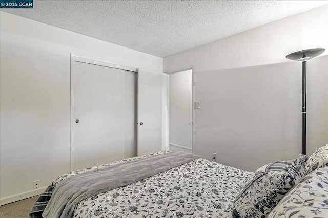 carpeted bedroom featuring a textured ceiling and a closet