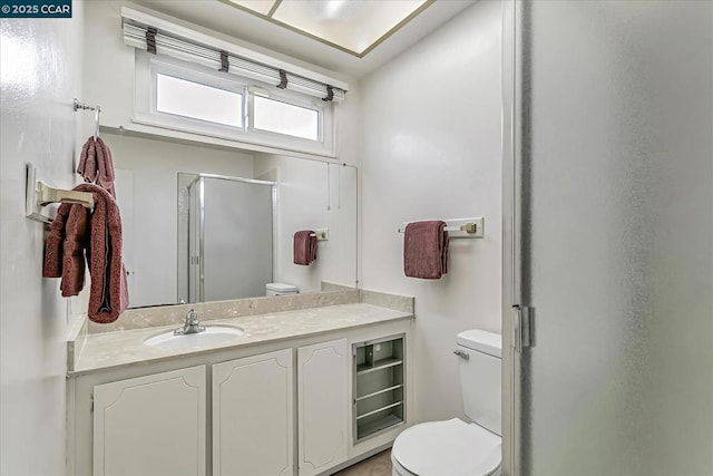 bathroom with toilet, vanity, and a shower with shower door