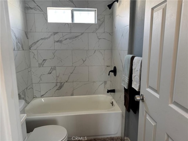 bathroom with tiled shower / bath combo and toilet