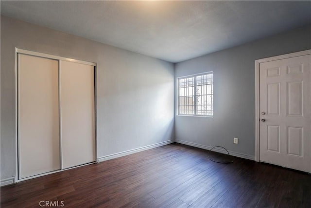 unfurnished bedroom featuring dark hardwood / wood-style flooring and a closet