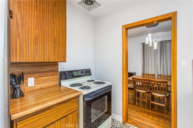 kitchen with electric range, decorative light fixtures, a chandelier, and light tile patterned floors