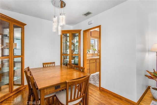 dining area featuring sink, light wood-type flooring, and a notable chandelier