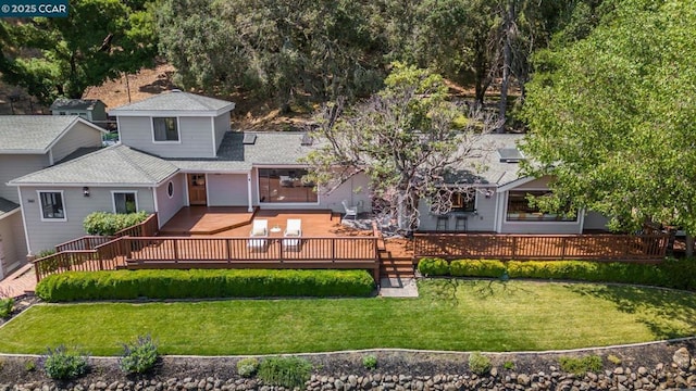 rear view of property featuring a wooden deck and a lawn