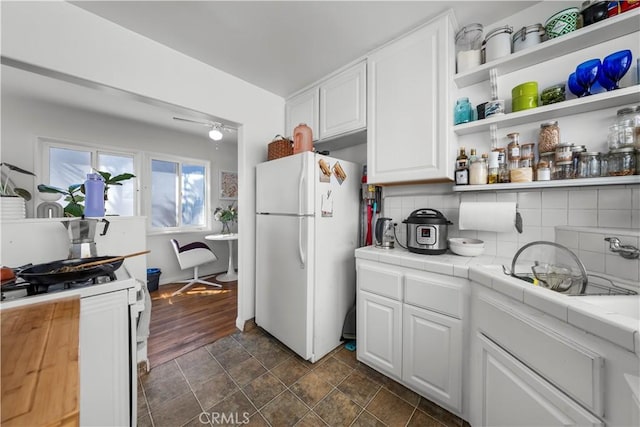 kitchen with white refrigerator, white cabinetry, tile counters, and decorative backsplash